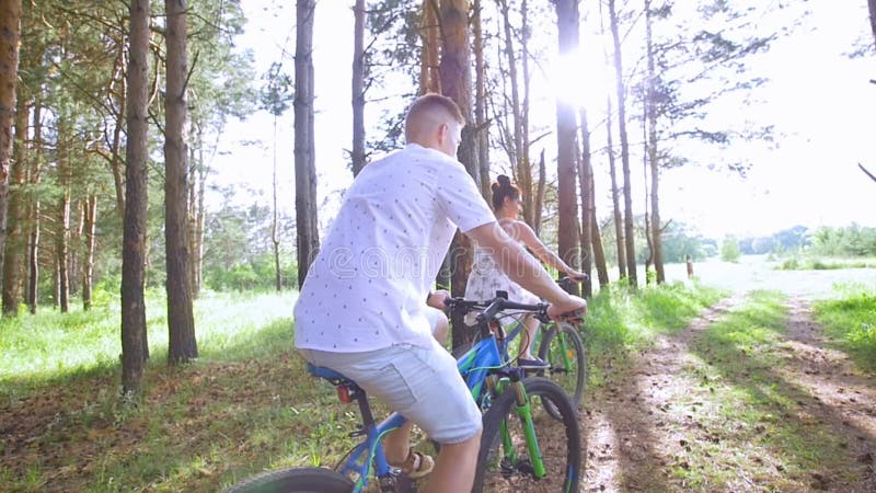 Ciclismo do homem novo e da mulher através da floresta do pinho