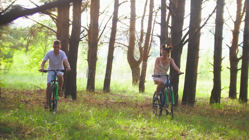 Ciclismo feliz dos pares no trajeto na floresta do pinho