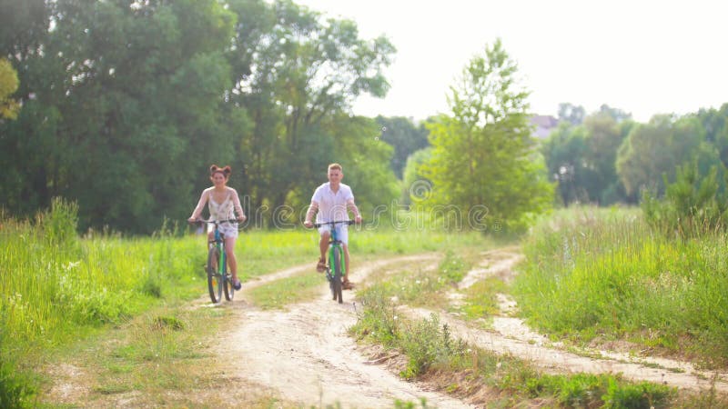 Ciclismo feliz dos pares no trajeto na floresta do pinho
