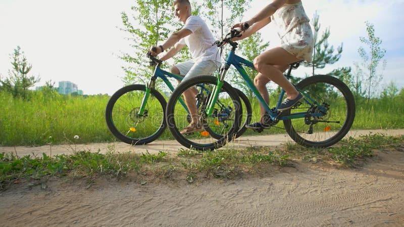 Ciclismo feliz novo dos pares no trajeto no campo do verão