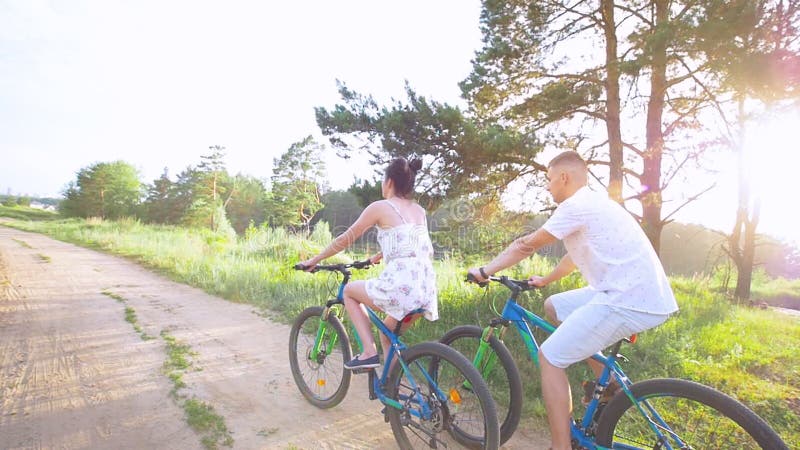 Ciclismo feliz novo dos pares no trajeto no campo do verão