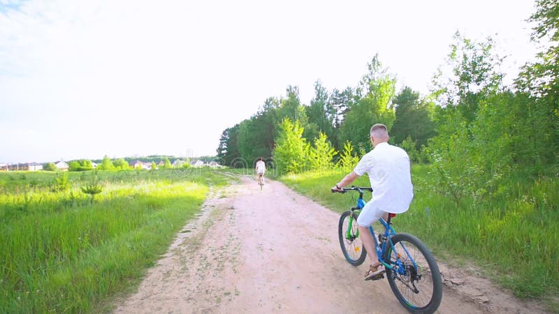 Ciclismo feliz novo dos pares no trajeto no campo do verão