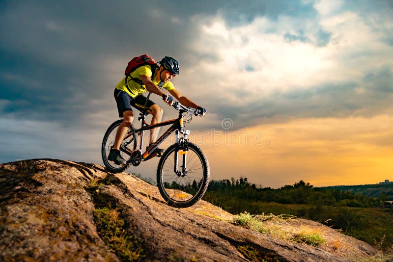 Ciclista che guida il mountain bike su Rocky Trail al tramonto Concetto estremo di ciclismo di enduro e di sport
