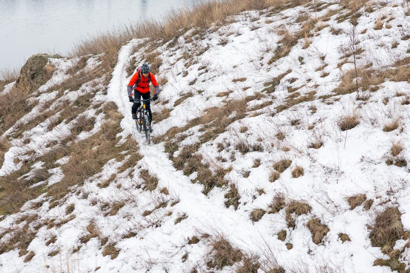 Ciclista en bici de montaña roja del montar a caballo en el rastro Nevado Deporte de invierno extremo y concepto Biking de Enduro fotos de archivo libres de regalías Ciclista en bici de montaña roja del montar a caballo en el rastro Nevado Deporte de invierno extremo y concepto Biking de Enduro fotos de archivo libres de regalías