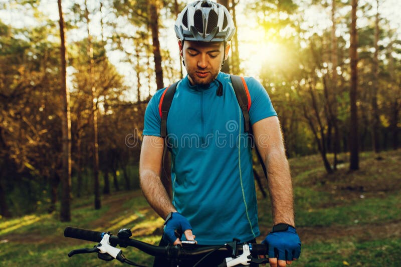 Ciclista europeu não barbeado novo no capacete, t-shirt de ciclagem azul vestindo, modo da velocidade de comutação das luvas em s fotografia de stock Ciclista europeu não barbeado novo no capacete, t-shirt de ciclagem azul vestindo, modo da velocidade de comutação das luvas em s fotografia de stock