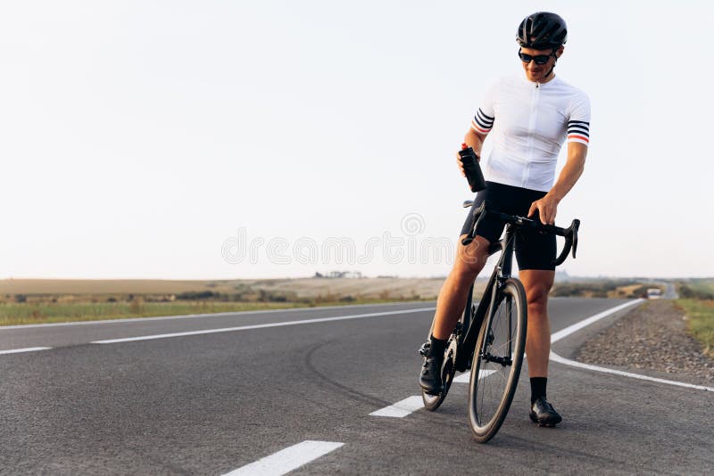 Hombre con casco y gafas sentado en bicicleta y sonriendo