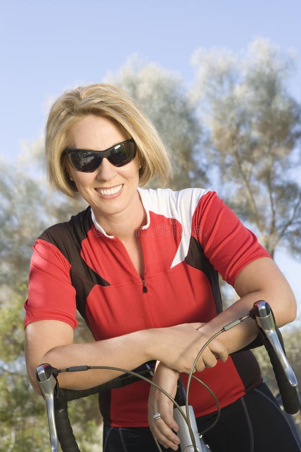 Ciclista femenino que se inclina en la bicicleta foto de archivo libre de regalías Ciclista femenino que se inclina en la bicicleta foto de archivo libre de regalías