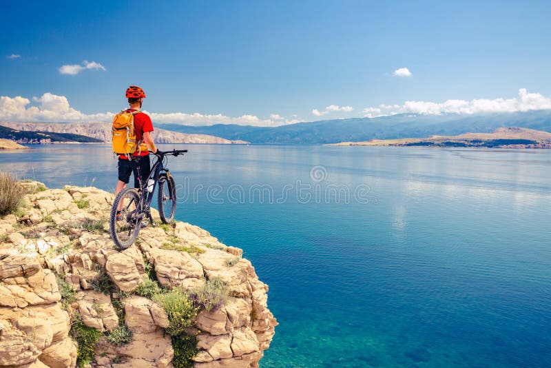 Ciclista in mountain-bike che esamina vista e che guida una bici fotografie stock libere da diritti Ciclista in mountain-bike che esamina vista e che guida una bici fotografie stock libere da diritti