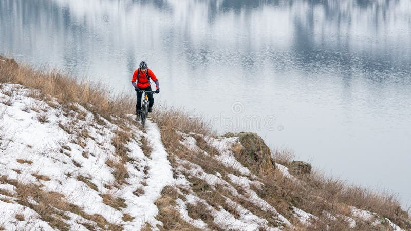 Ciclista no Mountain bike vermelho da equitação na fuga nevado Esporte de inverno extremo e conceito Biking de Enduro foto de stock royalty free Ciclista no Mountain bike vermelho da equitação na fuga nevado Esporte de inverno extremo e conceito Biking de Enduro foto de stock royalty free