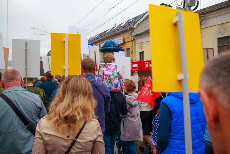 Cidade de Kaluga, Rússia - em maio de 2019: o forragem-tampão vestindo da menina assenta em ombros de seu pai e participa na para fotografia de stock royalty free Cidade de Kaluga, Rússia - em maio de 2019: o forragem-tampão vestindo da menina assenta em ombros de seu pai e participa na para fotografia de stock royalty free