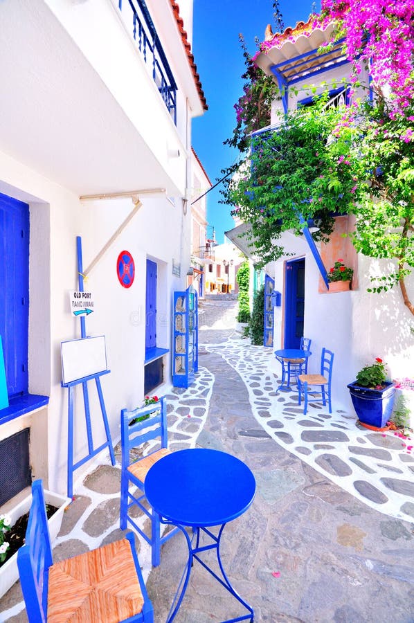 Cidade grega velha, ruas estreitas, paredes brancas, mobília azul e buganvília bonita