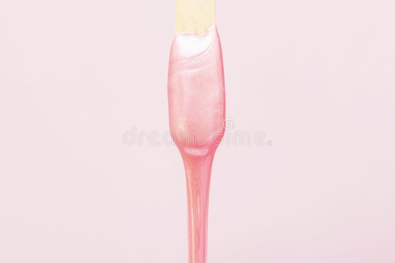 Liquid wax for pink depilation drains from the stick. The concept of depilation, waxing, smooth skin without hair. Liquid wax for pink depilation drains from the stick. The concept of depilation, waxing, smooth skin without hair