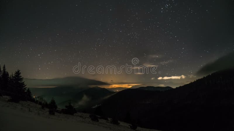 Ciel nocturne étoilé avec des étoiles et de bas nuages se déplaçant au-dessus des montagnes Le laps de temps bourdonnent dedans