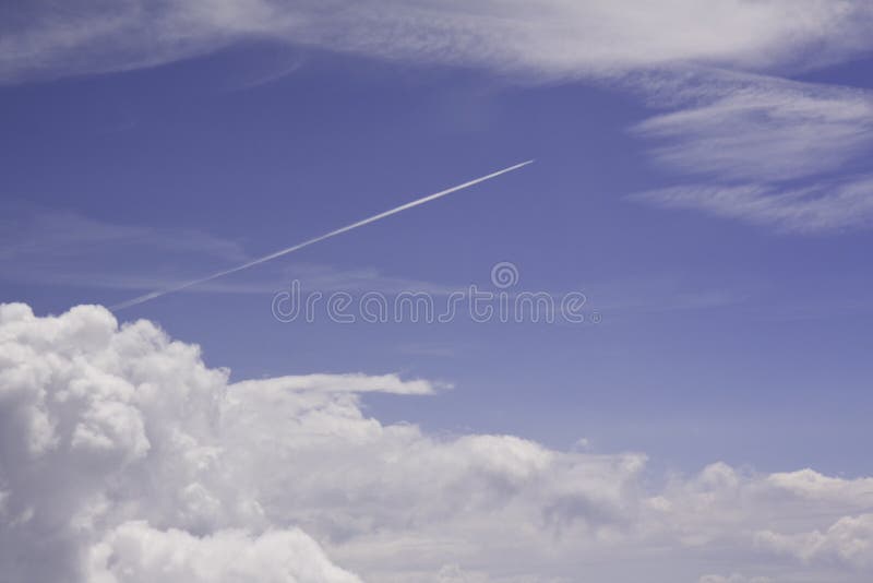 Cielo blu, nubi bianche e traccia di condensazione del jet