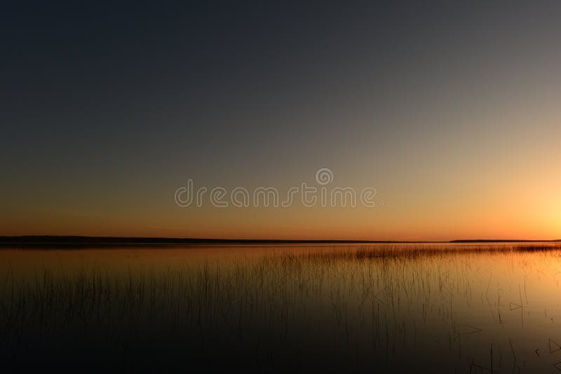 Cielo blu senza nuvole della primavera sopra il lago nei colori luminosi della luce e delle ombre di tramonto immagine stock Cielo blu senza nuvole della primavera sopra il lago nei colori luminosi della luce e delle ombre di tramonto immagine stock