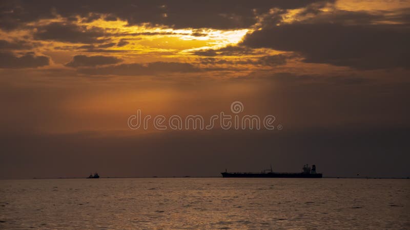 Cielo colorido de la puesta del sol en las nubes en el mar con las siluetas de naves imagen de archivo Cielo colorido de la puesta del sol en las nubes en el mar con las siluetas de naves imagen de archivo