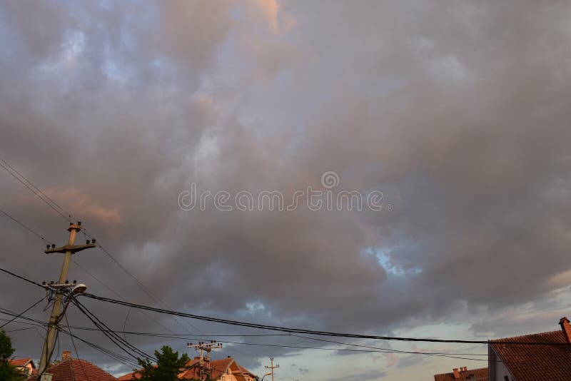 Above the sunlit roofs are gray clouds with a long, thin rainbow. Above the sunlit roofs are gray clouds with a long, thin rainbow