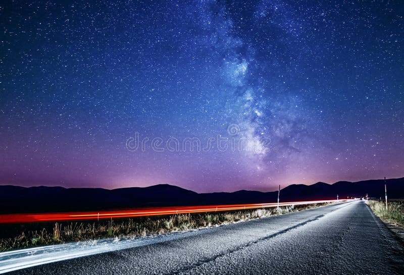 Cielo nocturno con la vía láctea y las estrellas Camino de la noche iluminado por el coche