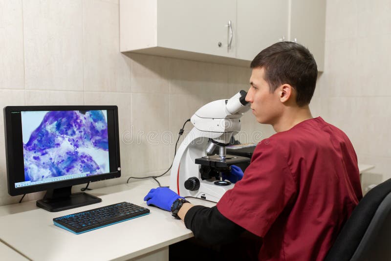 Cient?fico joven que mira a trav?s de un microscopio en un laboratorio Cient?fico joven que hace una cierta investigaci?n foto de archivo libre de regalías Cient?fico joven que mira a trav?s de un microscopio en un laboratorio Cient?fico joven que hace una cierta investigaci?n foto de archivo libre de regalías