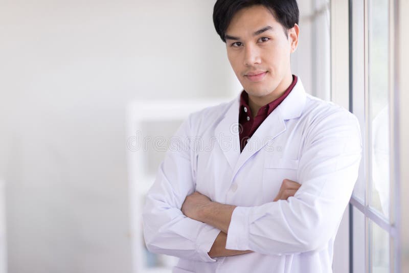 Asian scientists wear white robes standing by the window in the laboratory. And smiling at the camera. Asian scientists wear white robes standing by the window in the laboratory. And smiling at the camera