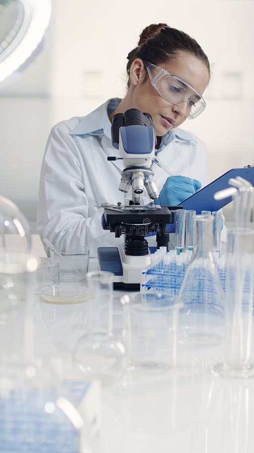 Científica trabajando con cultivo bacteriano con microscopio imagen de archivo