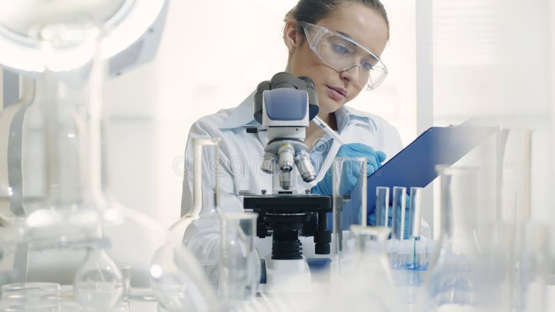 Científica trabajando en un laboratorio con un microscopio fotos de archivo