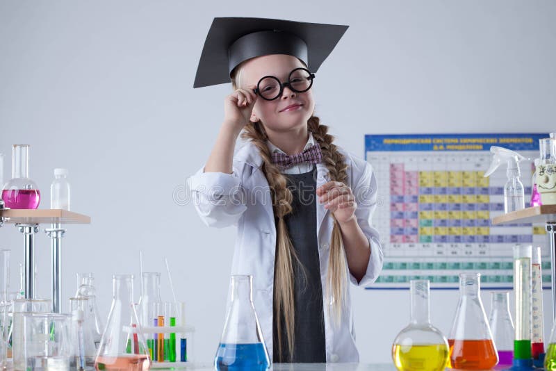Científico bastante pequeño que presenta con los vidrios en laboratorio fotos de archivo libres de regalías