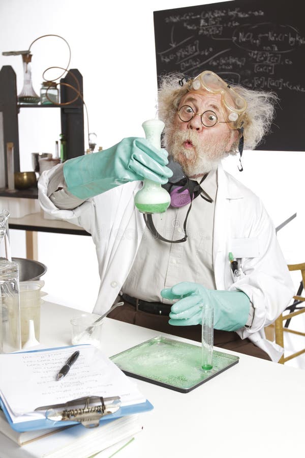 Amazed mad senior scientist in lab reacts to foaming green liquid overflowing beaker. Frizzy grey hair, round glasses, lab coat, aqua rubber gloves, blank blackboard, vertical, high key, copy space. Amazed mad senior scientist in lab reacts to foaming green liquid overflowing beaker. Frizzy grey hair, round glasses, lab coat, aqua rubber gloves, blank blackboard, vertical, high key, copy space.