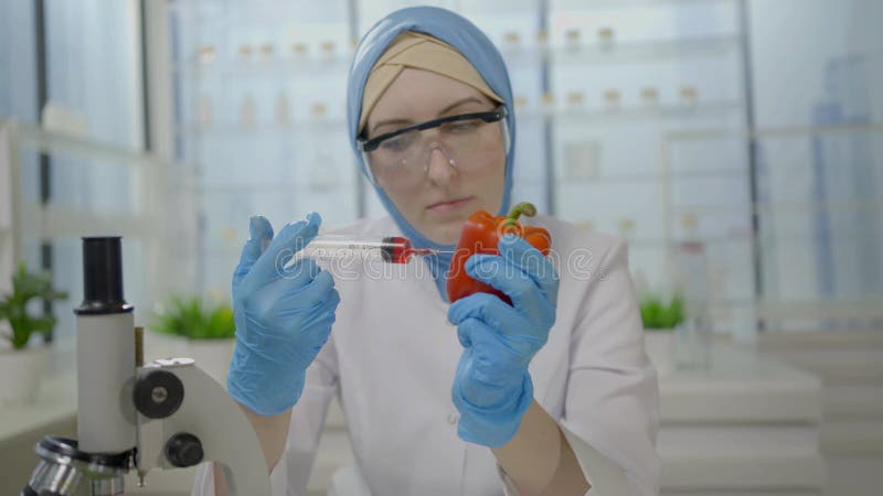 Científico musulmán sujetando una jeringa en sus manos haciendo una inyección