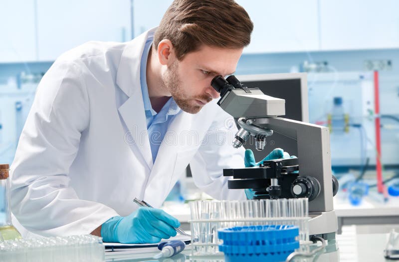 Científico que mira a través de un microscopio imagen de archivo Científico que mira a través de un microscopio imagen de archivo