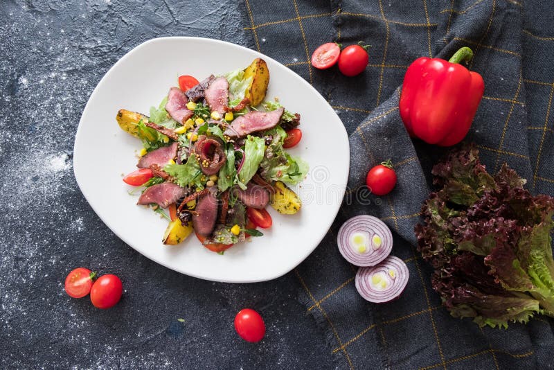 Ciep?a mi?sna sa?atka z arugula na bia?ym plateon zmroku kamienia tle Mieszkanie k?a?? z ingridients dla kucharza zdjęcia royalty free Ciep?a mi?sna sa?atka z arugula na bia?ym plateon zmroku kamienia tle Mieszkanie k?a?? z ingridients dla kucharza zdjęcia royalty free