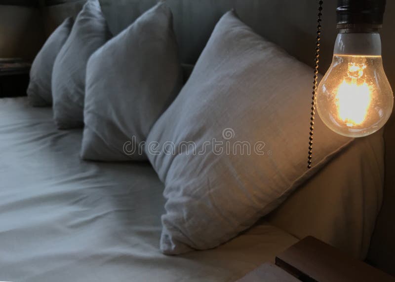 Ciepła pomarańczowa rozjarzona płonąca żarówka na głowie biały drewniany łóżko Loft Wewnętrznego projekt i relaksuje, wygodnego