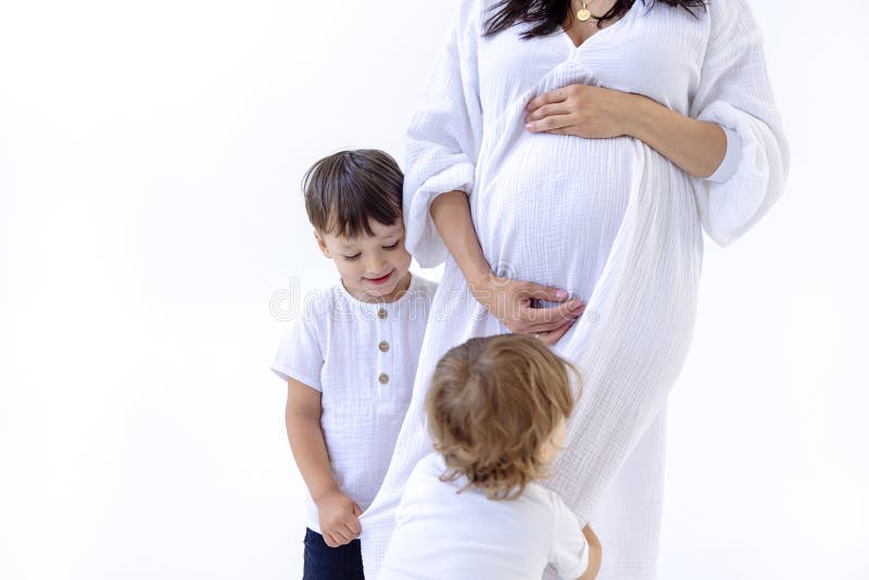Cierre de brazos y vientre de una joven embarazada y sus dulces hijos. los niños abraza a su madre. gentiles toques de adoración fotos de archivo libres de regalías