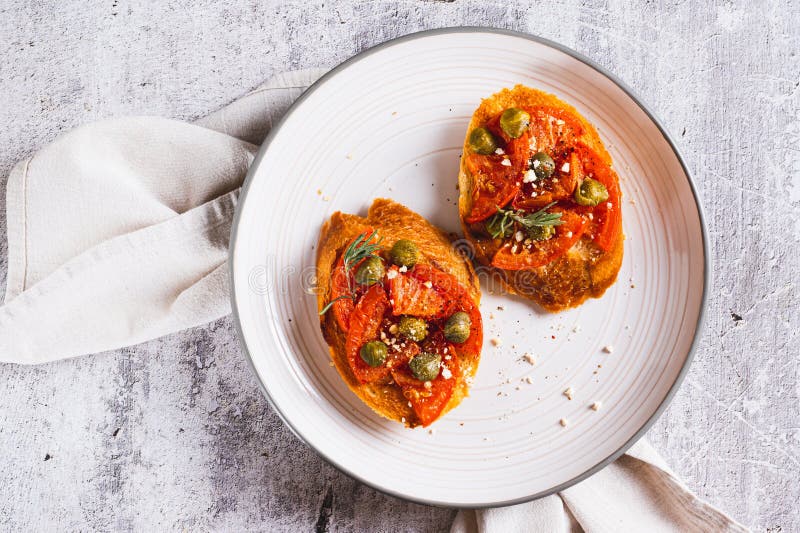 Cierre de la bruschetta con tomates secos y alcaparras en un plato en la mesa superior