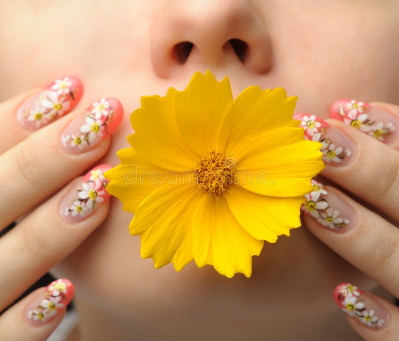 Female face close up c flower in a mouth and nail art. Figure of camomiles on nails. Female face close up c flower in a mouth and nail art. Figure of camomiles on nails