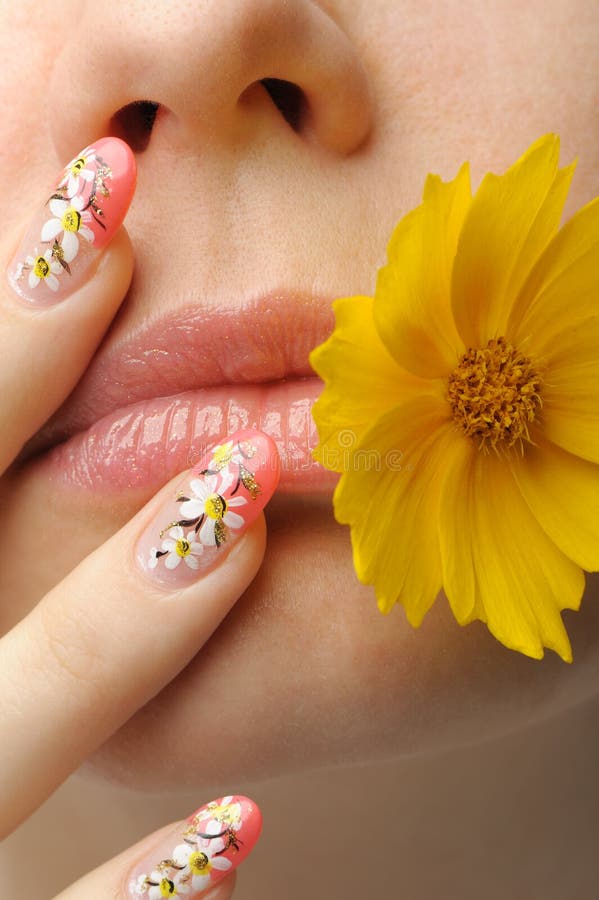 Female face close up c flower in a mouth and nail art. Figure of camomiles on nails. Female face close up c flower in a mouth and nail art. Figure of camomiles on nails