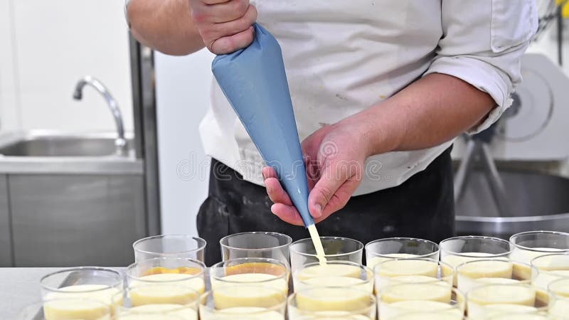 Cierre de la crema vertiginosa del chef con bolsita de pastelería a cuenco de vidrio. almacen de metraje de vídeo