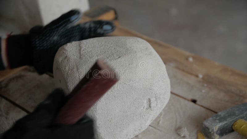 Cierre de las manos de los hombres haciendo una escultura de piedra con papel de lija.