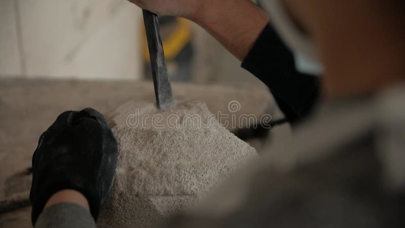 Cierre de las manos de los hombres haciendo una escultura de piedra con un cincel.