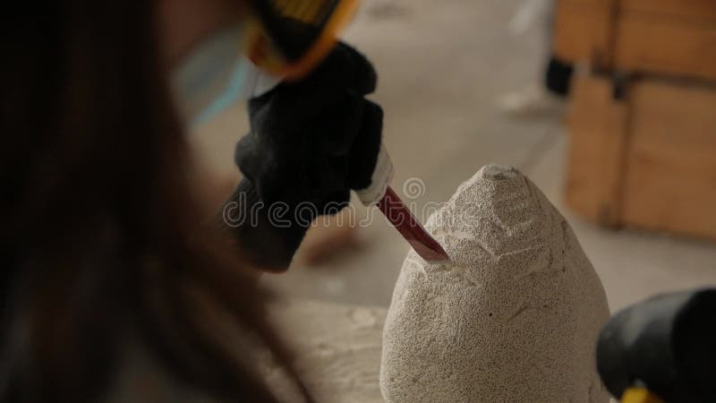 Cierre de las manos de los hombres haciendo una escultura de piedra en un taller.