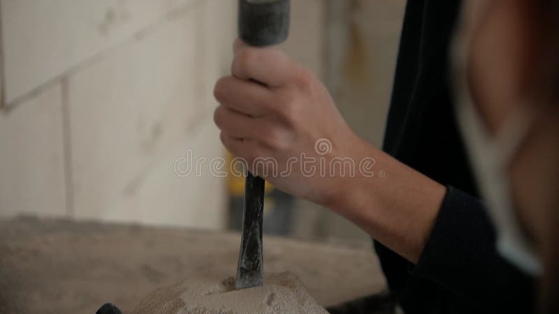 Cierre de las manos de los hombres haciendo una escultura de piedra en un taller.