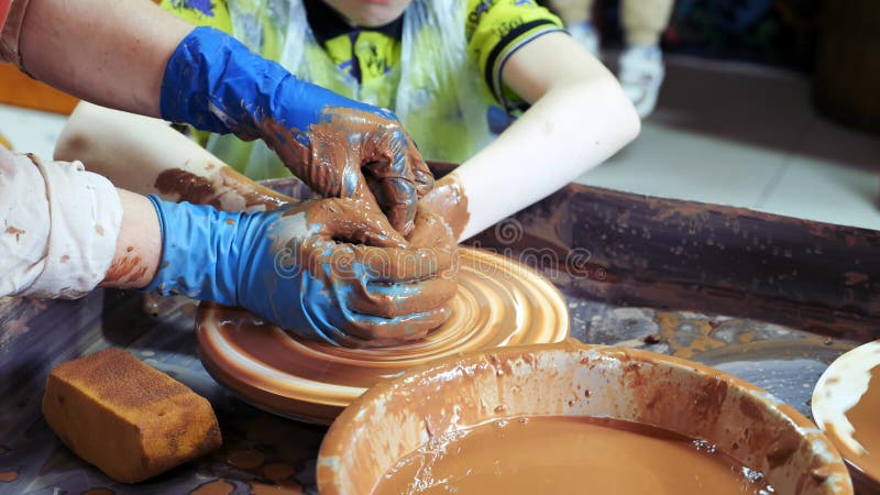 Cierre de las manos de los niños esculpiendo platos de cerámica de arcilla en el taller. almacen de video