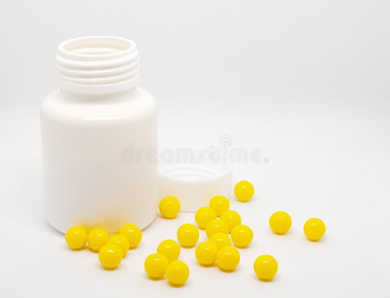 Cierre de las vitaminas de los dragones amarillos esparcidas cerca de una botella de plástico abierta sobre un fondo blanco fotos de archivo libres de regalías Cierre de las vitaminas de los dragones amarillos esparcidas cerca de una botella de plástico abierta sobre un fondo blanco fotos de archivo libres de regalías