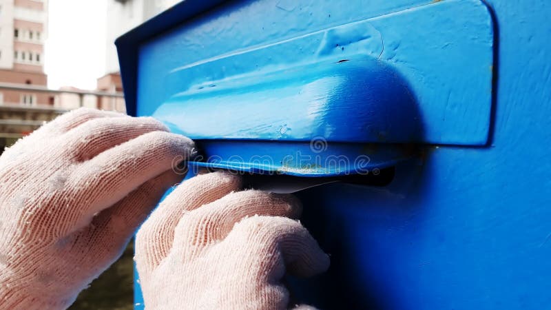 Cierre de manos de niños tirar una carta en una caja de correo azul.
