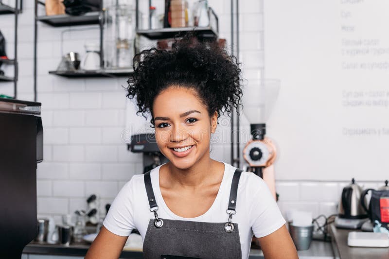 Cierre de un joven barista sonriente con pelo rizado imagenes de archivo