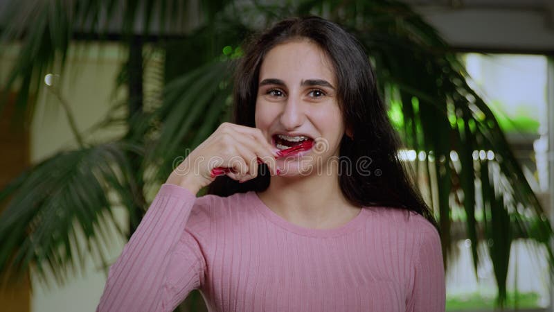 Cierre de una joven de aspecto oriental que se cepilla los dientes con un cepillo de dientes. niña en bronce foto de archivo