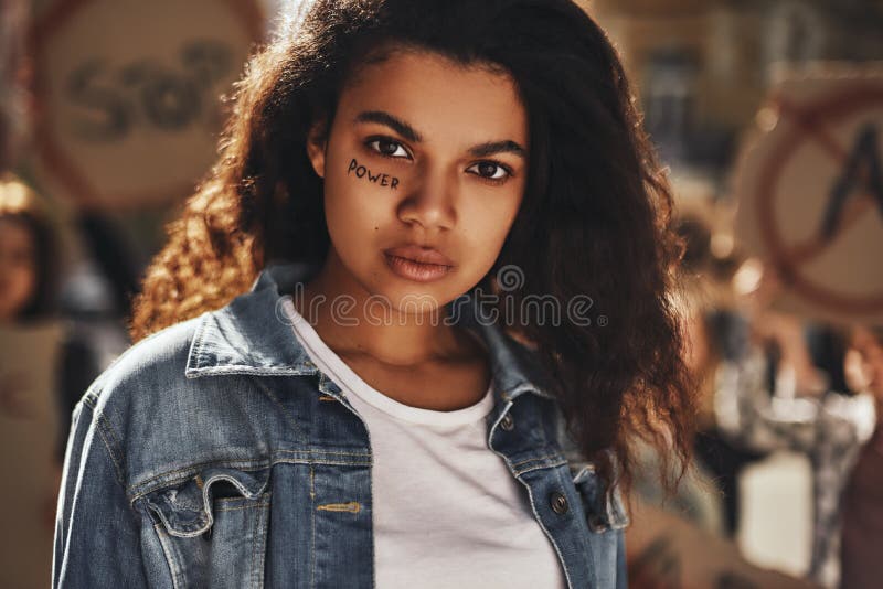 Cierre de una mujer afroamericana con poder de palabra mirando una cámara mientras protestaba con un grupo de mujeres activistas fotos de archivo