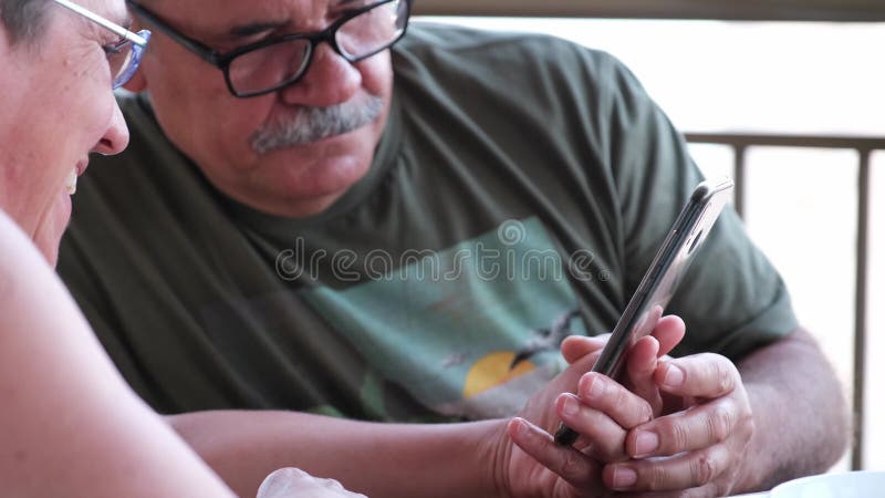 Cierre de una pareja madura viendo algo en su smartphone almacen de metraje de vídeo
