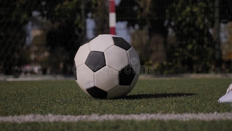 Cierre de una pelota de fútbol sobre una hierba verde un niño pone su pie en la pelota almacen de metraje de vídeo