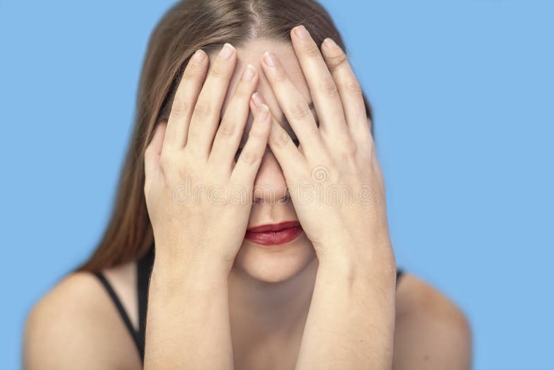Cierre el retrato de una joven caucásica cubriéndose la cara con las manos foto de archivo Cierre el retrato de una joven caucásica cubriéndose la cara con las manos foto de archivo